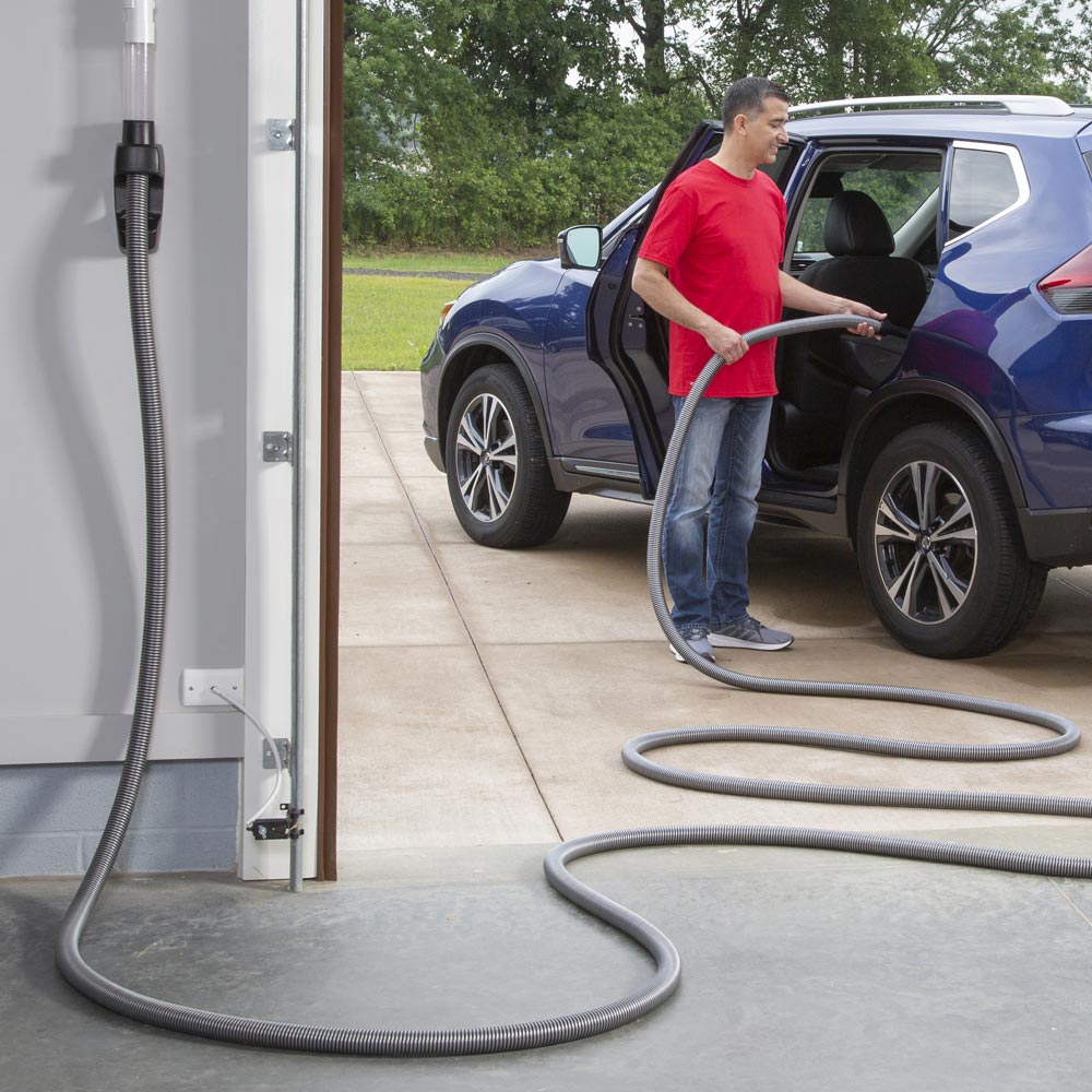 Man vacuuming his SUV in the driveway with a retractable garage hose